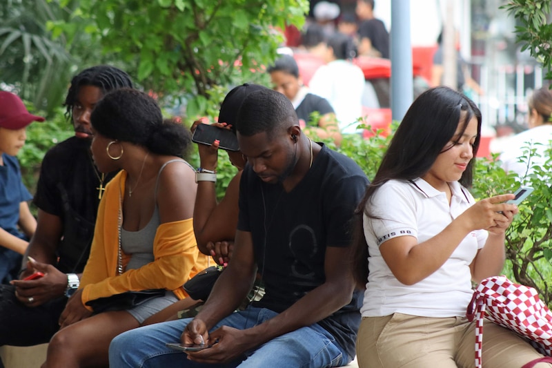 Jóvenes usando sus teléfonos móviles en la ciudad