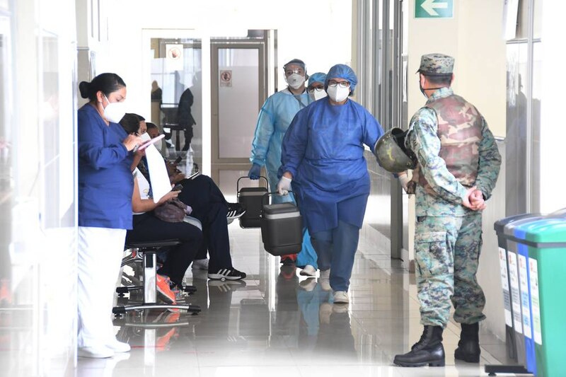 Personal médico transporta una caja con vacunas contra el COVID-19