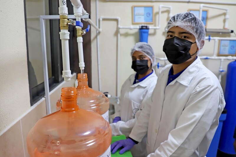 Estudiantes del TESChi llenando garrafones de agua purificada en la planta “Aguaquim”, un proyecto innovador de impacto comunitario.