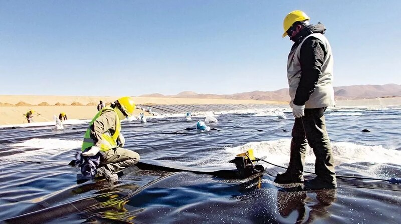 Trabajadores instalando un geomembrana en un depósito de relaves mineros