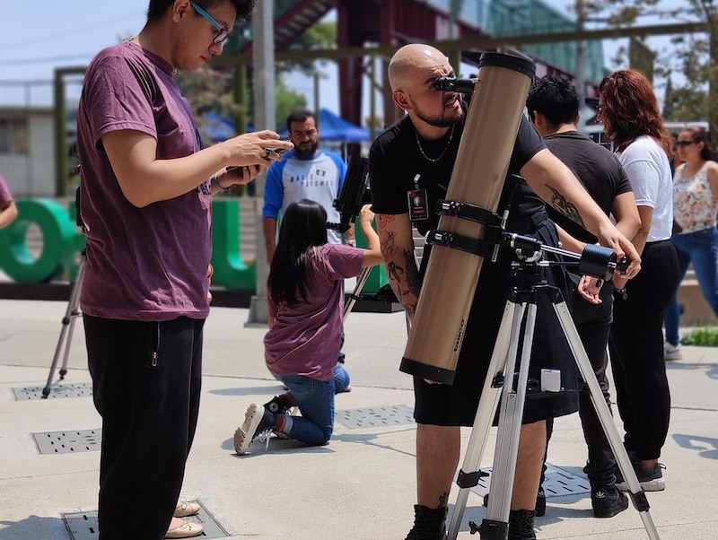 Un grupo de personas observa el cielo con un telescopio.