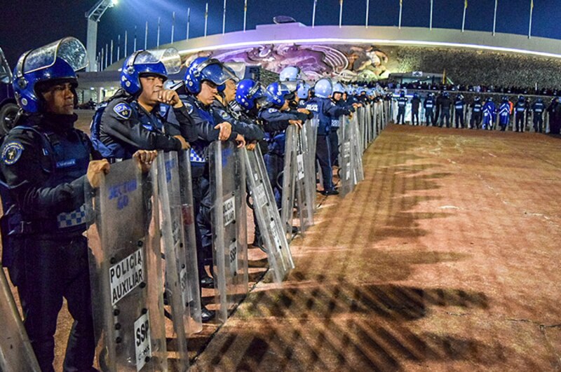Policías antimotines mexicanos forman una valla para contener a los aficionados en un partido de fútbol.