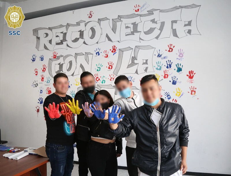 Jóvenes en un centro de detención pintan un mural como parte de un programa de reinserción social.