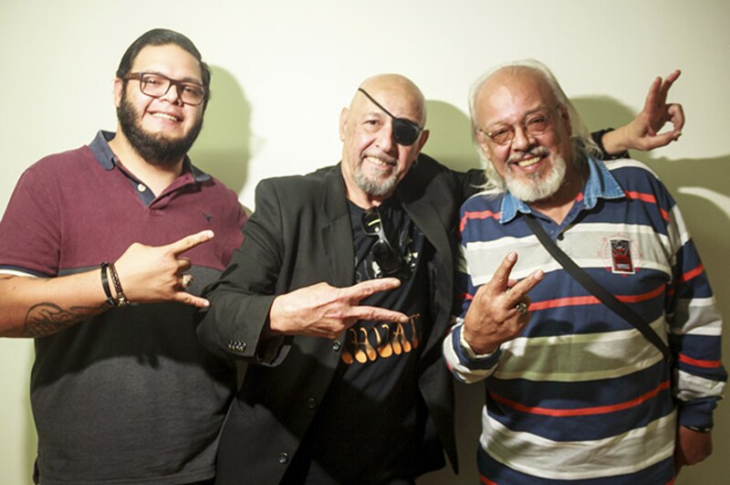 Tres hombres sonrientes haciendo el signo de la paz.