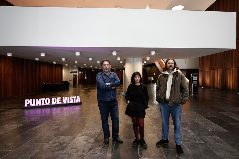 Tres personas posando en el interior de un edificio