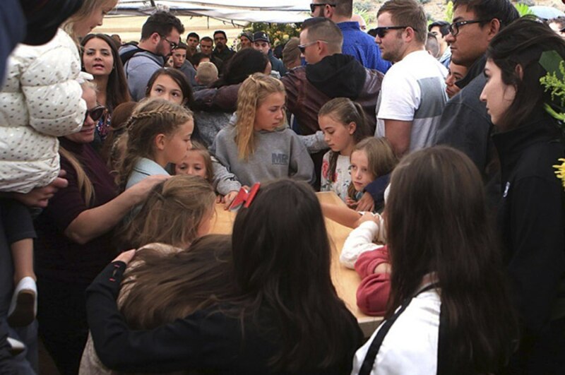 Multitud de personas se reúne alrededor de una mesa en un evento al aire libre