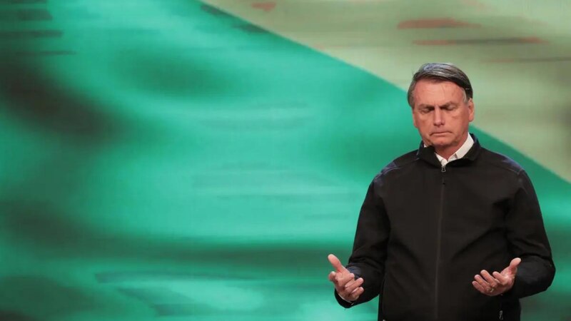 El presidente Jair Bolsonaro hace un discurso ante la bandera de Brasil.