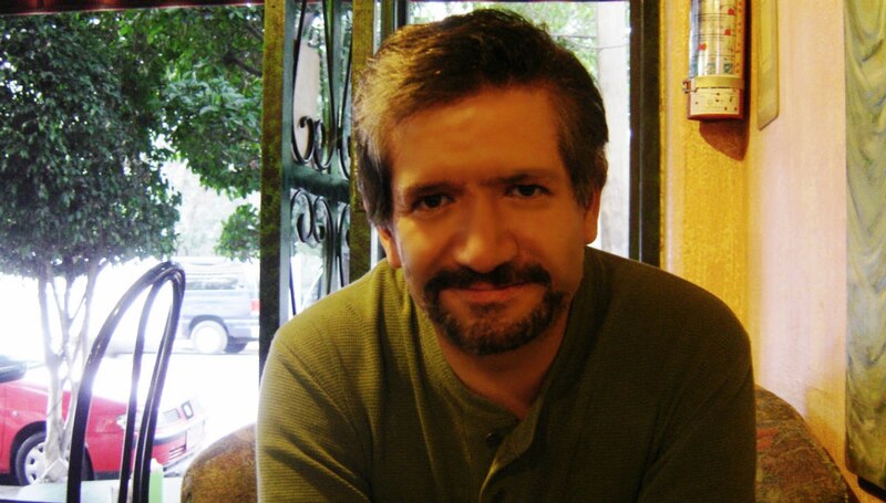 Un hombre barbudo sonríe a la cámara.
