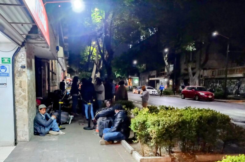 Un grupo de personas esperando en la calle por la noche