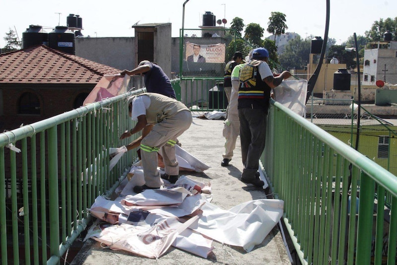 Trabajadores retiran propaganda electoral de un puente peatonal