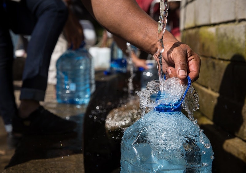 Una persona llena una botella de agua de una fuente pública.