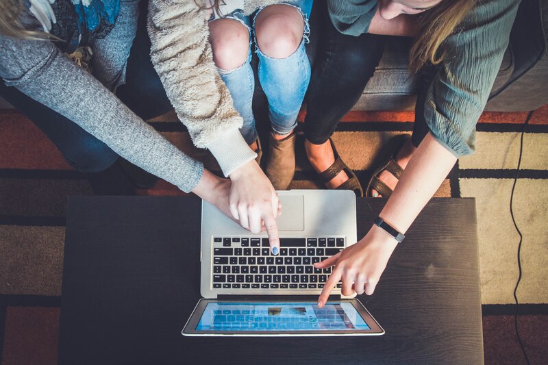 Tres mujeres jóvenes usan una computadora portátil