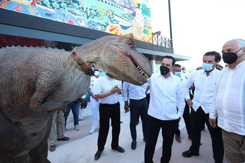 El gobernador de Quintana Roo, Carlos Joaquín, saluda a un dinosaurio en el Museo de Historia Natural de Cancún.
