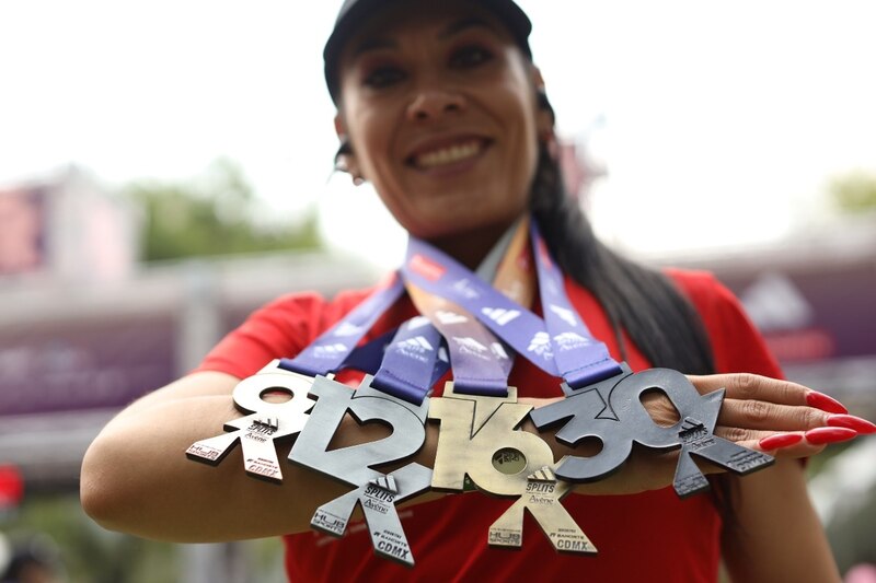 Mujer corredora mostrando sus medallas de las series de Adidas Splits
