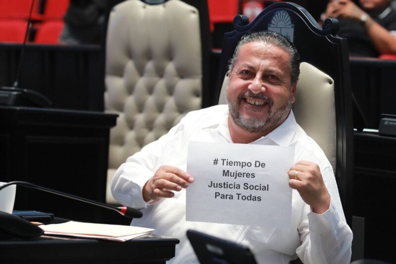 El senador Ricardo Monreal sostiene un cartel que dice "#TiempoDeMujeres Justicia Social Para Todas"