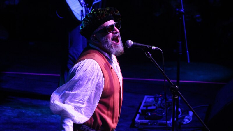 Un cantante con gafas de sol canta en un escenario