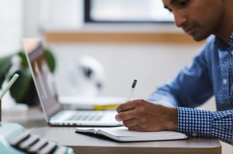 Un hombre escribiendo en un cuaderno