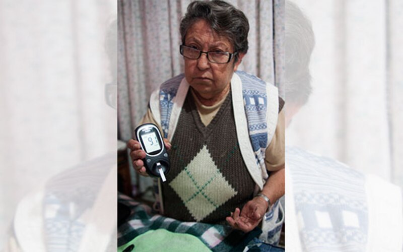 Mujer mayor usando un medidor de glucosa en sangre