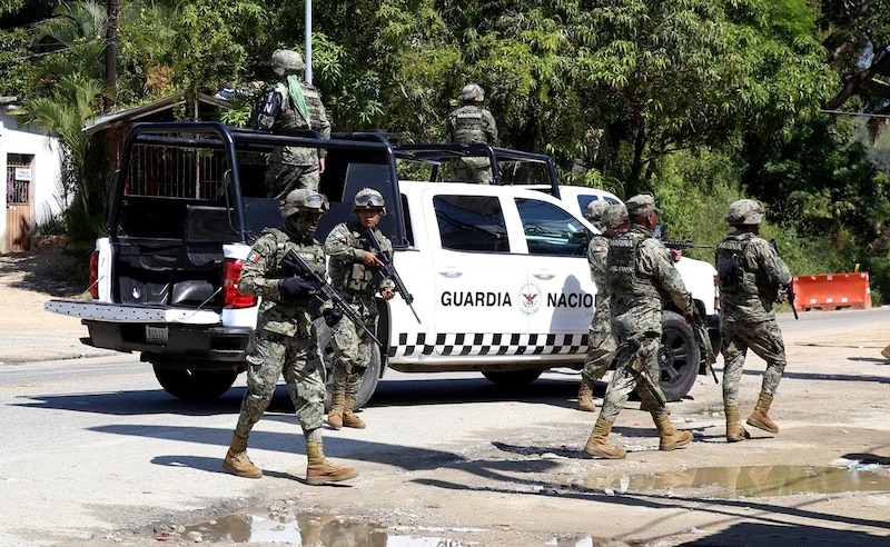 Militares mexicanos patrullan una calle en una ciudad.