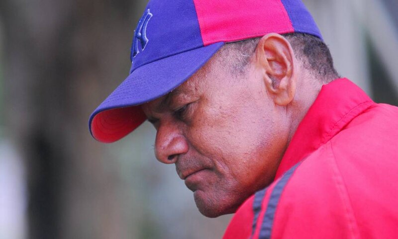 Un hombre con una gorra de béisbol azul y roja se tapa la cara con la mano