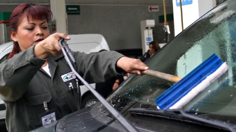 Mujer limpiando el parabrisas de un coche