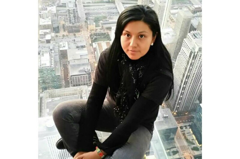 Mujer sentada en el borde de un edificio alto con la ciudad de Chicago de fondo