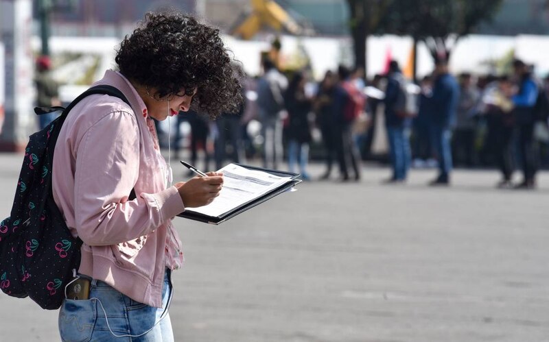 Jovencita rellenando un formulario en la calle