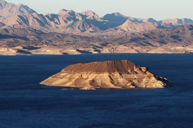 Una isla en medio de un lago con montañas al fondo