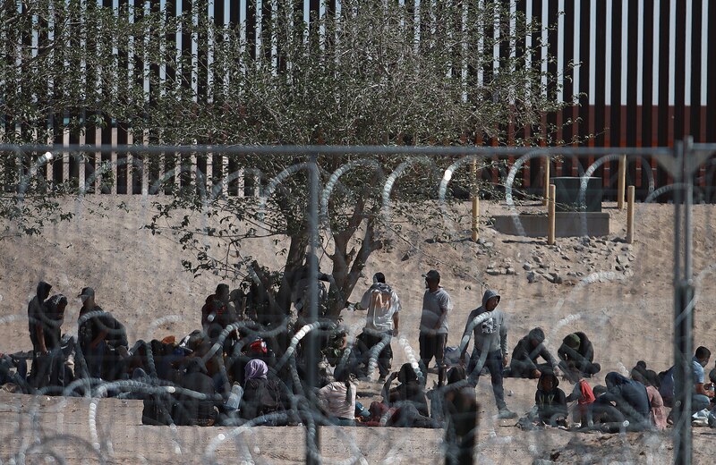 Migrantes descansan a la sombra de un árbol en la frontera entre México y Estados Unidos