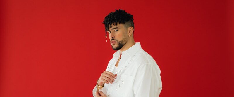 Maluma, el cantante colombiano de música urbana, posa para una foto con un fondo rojo.