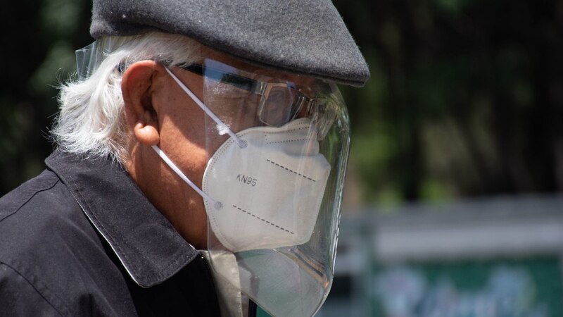 Adulto mayor con mascarilla y careta facial