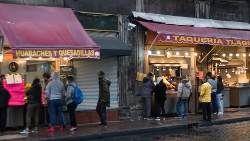 Larga fila de personas esperando para comprar comida en un puesto callejero en México