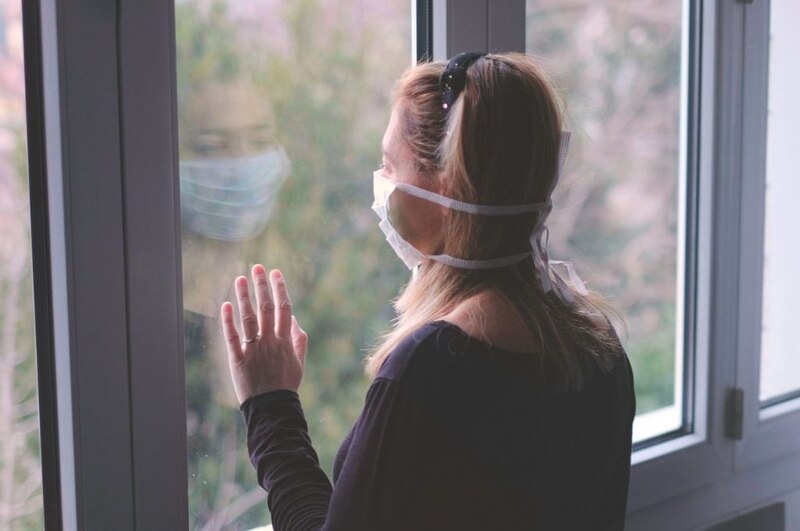 Mujer mirando por la ventana durante la cuarentena