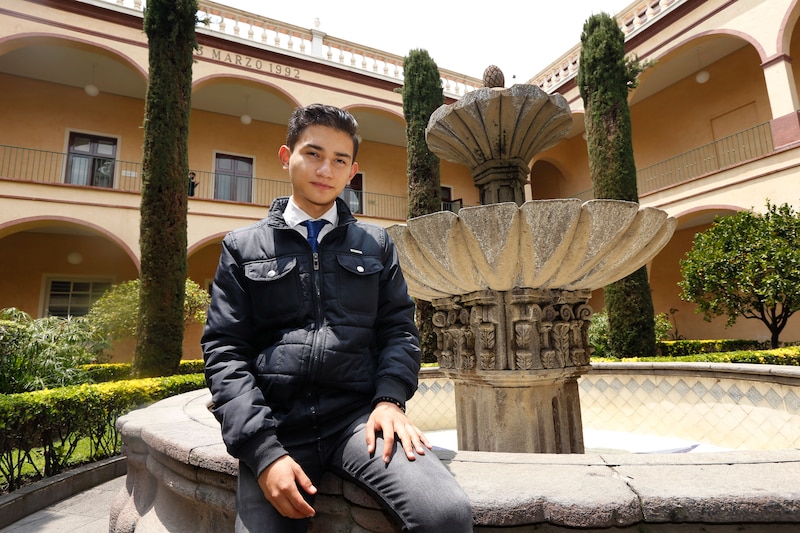 Un joven estudiante sentado en una fuente.