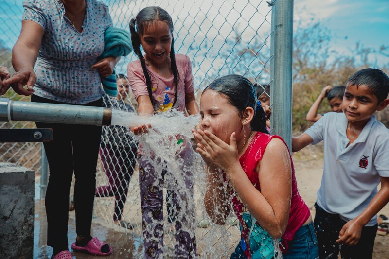 Niños de La Cascada bebiendo agua potable en su comunidad tras la instalación de un pozo y tubería comunitaria