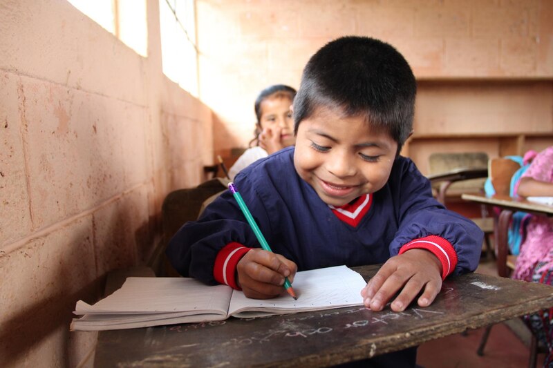 Niño indígena escribe en su cuaderno