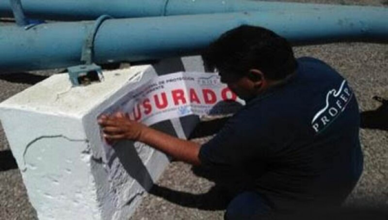 Un trabajador coloca una señal de advertencia en una tubería.