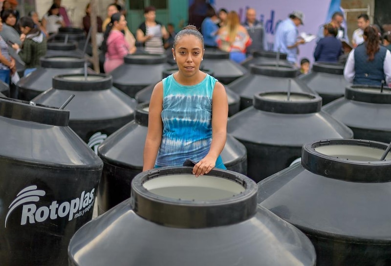 Mujer junto a tanques de agua