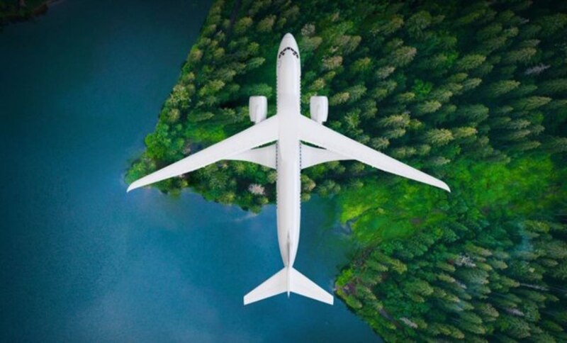 Un avión vuela sobre un bosque verde y un lago azul.