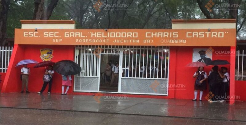 Estudiantes se protegen de la lluvia a las afueras de la escuela secundaria general "Heliodoro Charis Castro" en Juchitán, Oaxaca.