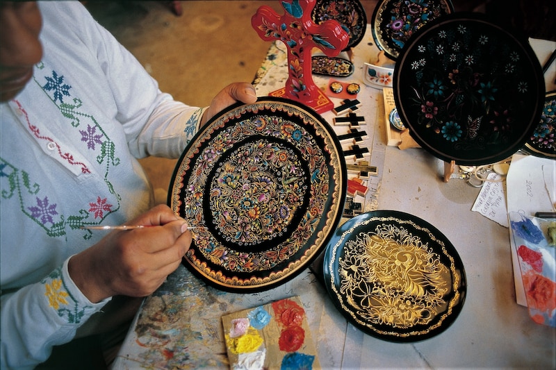 Artesana mexicana pinta un plato de barro negro