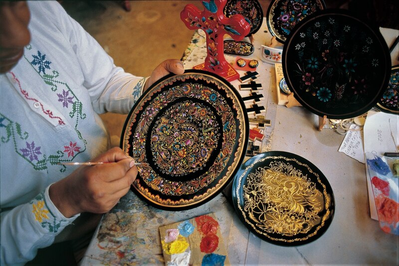 Artesana mexicana pinta un plato de barro negro