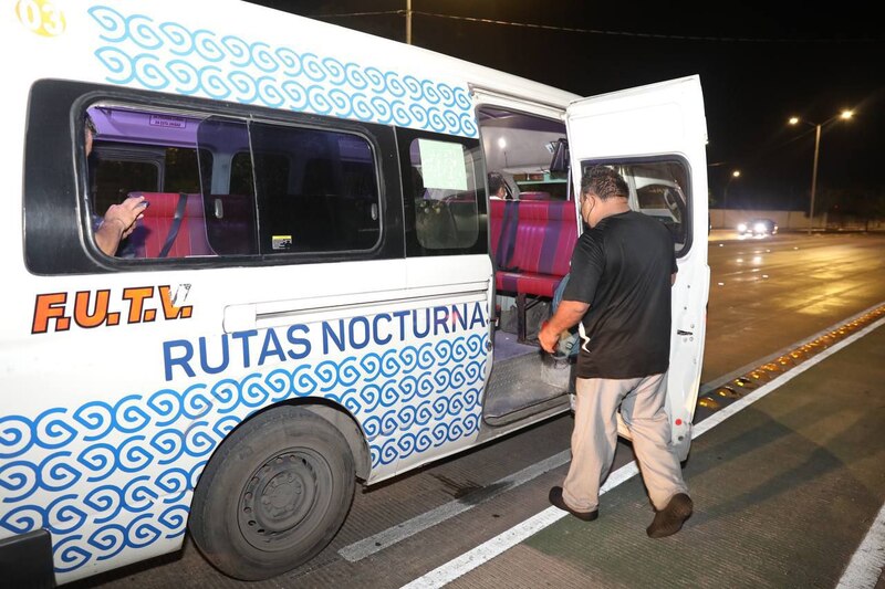 Un hombre baja de un autobús nocturno en una calle de la ciudad.