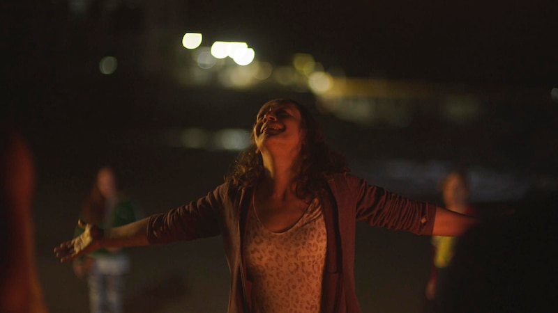 Mujer joven bailando en la playa de noche