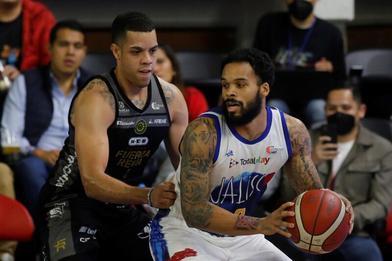 Dos jugadores de baloncesto se enfrentan en la duela.