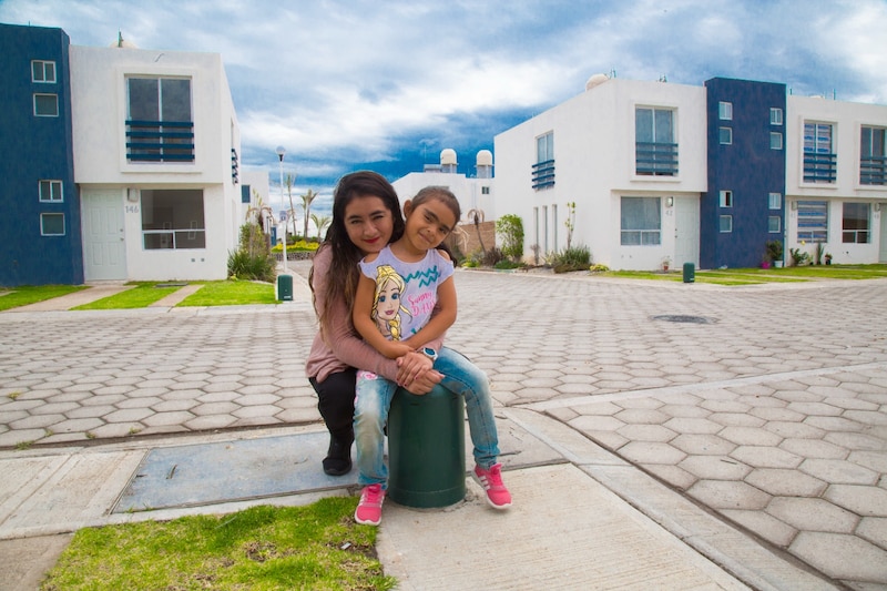 Madre e hija sonríen abrazadas en la entrada de su casa