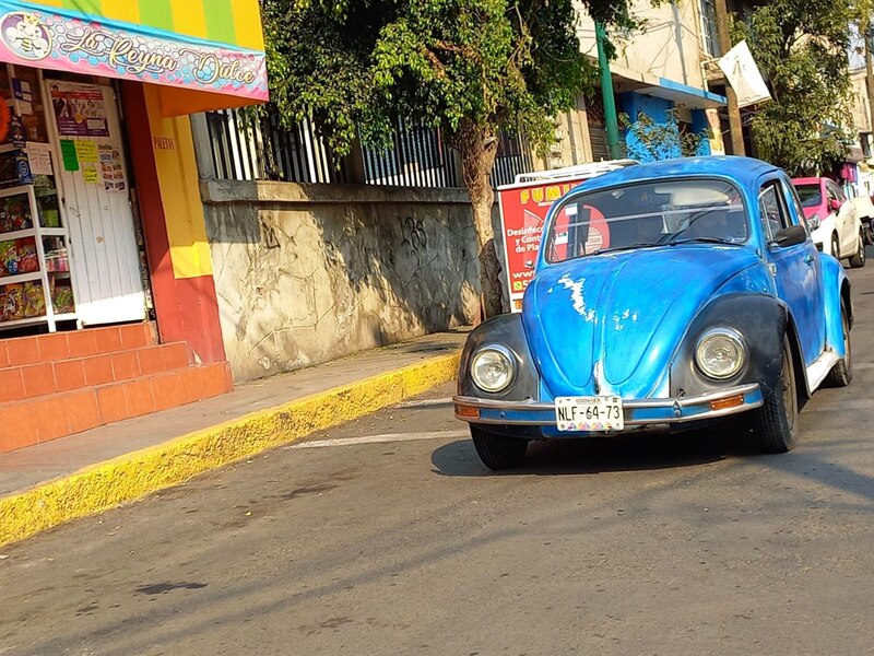 Un Volkswagen Sedán azul clásico estacionado en una calle de México