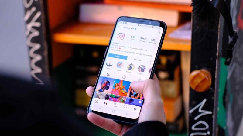 Una mujer sostiene un teléfono inteligente en la mano y mira la pantalla.