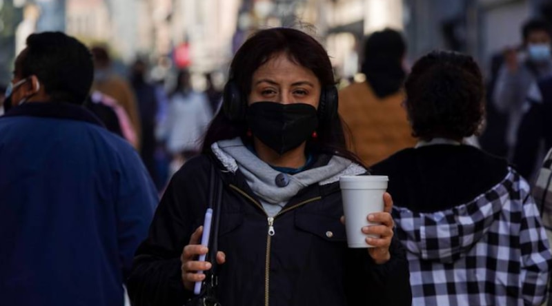 Mujer con cubrebocas y café en la mano