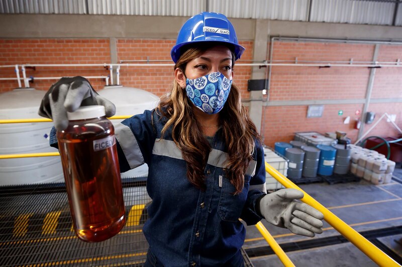 Mujer sosteniendo una botella de aceite usado